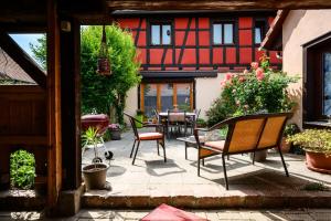 a patio with chairs and a table and a building at Gîte Le Nain Rouge in Kaysersberg