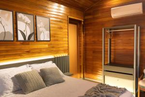 a bedroom with wooden walls and a bed and a television at Cabana Altavista in Flores da Cunha +18 photos