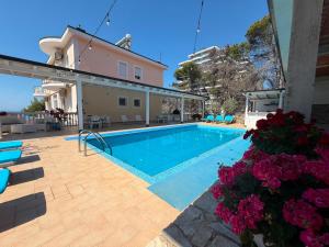 a swimming pool with flowers and a house at Hotel Gezimi in Shëngjin +28 photos