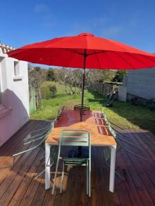 a wooden table with a red umbrella on a deck at l'Herbo' MAGNIFIQUE maison à 2 pas du port de Pêche in LʼHerbaudière