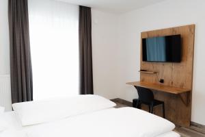 a room with two beds and a desk with a tv at ML Business Hotel - Self-Check-in in Lannach