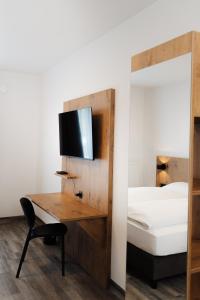 a bedroom with a bed and a desk with a television at ML Business Hotel - Self-Check-in in Lannach +6 photos