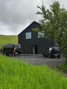 two cars parked in front of a black building at Tindasel - The Farm in Hella