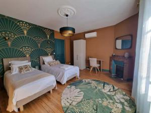 a bedroom with two beds and a fireplace at Le Logis de Placide in Tarbes