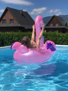 a young girl is riding on a pink raft in a pool at Víkendové Chalupy in Liptovský Trnovec