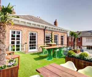 an outdoor patio with grass and a table and chairs at Oddfellows Chester Hotel & Apartments in Chester