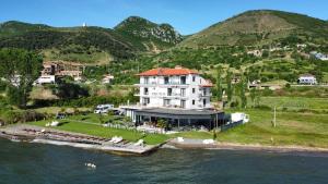 a large white house on a island in the water at Hotel Victoria in Pogradec