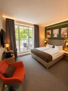 a bedroom with a bed and a chair and a window at Hotel Stempferhof in Gößweinstein +59 photos