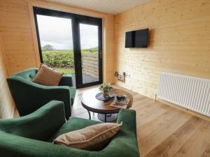 a living room with two chairs and a table and a television at Alken The Stag in Bushmills