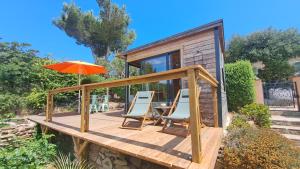 a wooden deck with chairs and an umbrella at L'Alizé du Levant in Île du Levant