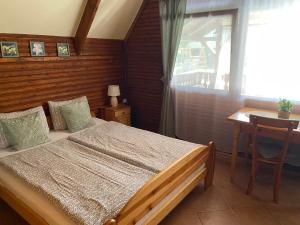 a bedroom with a bed and a table and a window at Őzike Apartmanházak in Bogács