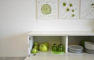 a white cabinet with green dishes and plates at Myama Lake in Desenzano del Garda