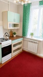 a kitchen with white cabinets and a red rug at квартира жубанова in Aktobe