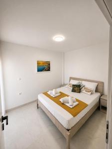 a white bedroom with a large bed with towels on it at Apartmani Morѐll 1 in Novalja