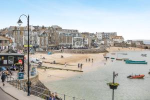 a group of people on a beach with buildings and water at 1 Bed in St. Ives oc-pc466a in St Ives