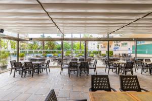 an outdoor patio with tables and chairs and windows at Rentalmar Pineda Suites in La Pineda