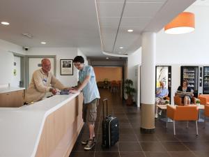 two men standing at a counter in a waiting room at ibis budget Brugge Centrum Station in Bruges