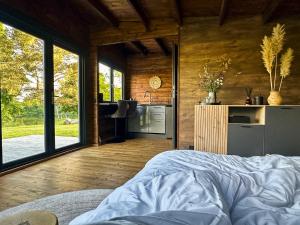 a bedroom with a bed and a kitchen with windows at Black Cat House Radailiai in Radailiai