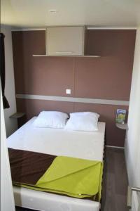 a small bed with two pillows on it in a room at Kabana Village in Saint-Hilaire-de-Riez