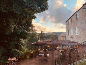 a deck with chairs and umbrellas and a building at Bastide en Margeride in Châteauneuf-de-Randon