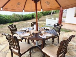 a wooden table with chairs and an umbrella at Kilulu Luxury Island, Watamu in Watamu
