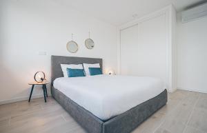 a white bedroom with a large bed with blue pillows at Villa Delfina with private pool in Mariquiteira