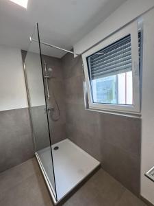 a bathroom with a glass shower with a window at Bayman Apartments in Ellhofen