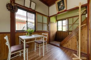 a room with a table and chairs and a staircase at ゲストハウス五郎平 in Nagahama