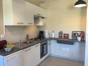 a kitchen with white cabinets and a sink at Le petit scevolles in Verrue