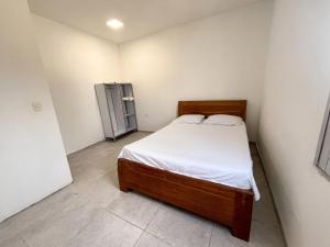 a small bedroom with a bed and a refrigerator at La Casita Rooms - Habitaciones Coveñas in Coveñas +1 photo