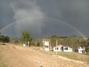 a rainbow in the sky over a dirt road at Luna Llena in Suesca