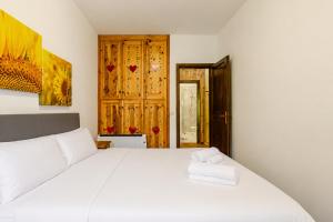 a bedroom with a white bed with two towels on it at Eldann Apartment - Tradizione e Relax a Sappada in Sappada +7 photos