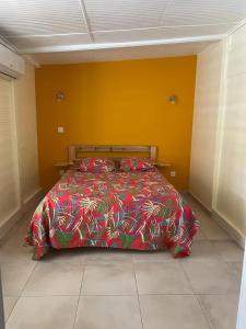 a bedroom with a bed with a colorful comforter at Gites vallée des caraibes in Bouillante