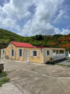 a small yellow house with a red roof at Gites vallée des caraibes in Bouillante