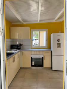a kitchen with yellow walls and a white refrigerator at Gites vallée des caraibes in Bouillante +9 photos