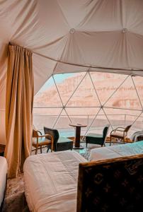 a room with two beds and chairs in a tent at Desert Hello Camp in Wadi Rum