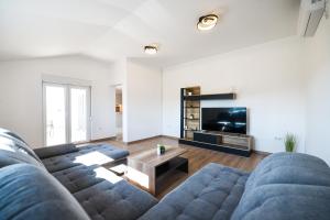 a living room with a blue couch and a television at OLEA Holiday Home Benkovac-private pool,garden and parking in Šopot