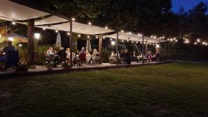 a group of people sitting at tables under a tent at night at Albergo Pian del Bosco in Novafeltria