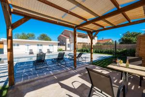 a patio with chairs and a table and a pool at OLEA Holiday Home Benkovac-private pool,garden and parking in Šopot