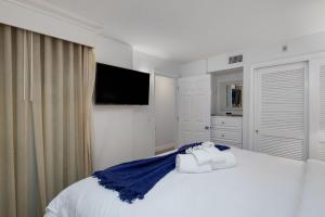 a white bedroom with a bed with towels on it at Beach Villa 2323 - Captiva One Bedroom Deluxe Beachfront Residence in Captiva