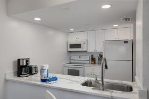 a white kitchen with a sink and a refrigerator at Beach Villa 2323 - Captiva One Bedroom Deluxe Beachfront Residence in Captiva