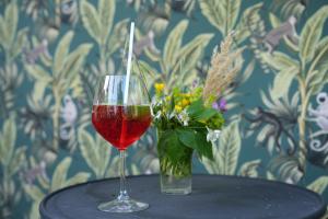a glass of wine and a vase of flowers on a table at Albergo Pian del Bosco in Novafeltria