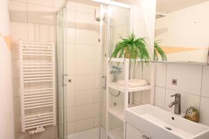 a white bathroom with a shower and a sink at FeWo Renken in Trassenheide +36 photos