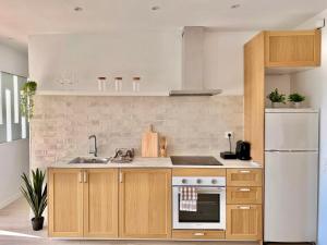a kitchen with wooden cabinets and a white refrigerator at Cala Crancs - Sea Views in Salou