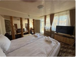 a bedroom with a bed and a flat screen tv at Guest House Скиора in Chepelare