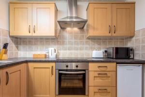 a kitchen with wooden cabinets and a stove top oven at Prestwick Central - Donnini Apartments in Prestwick