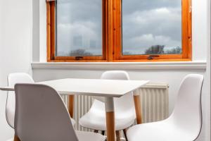 a white table and chairs in a room with a window at Prestwick Central - Donnini Apartments in Prestwick +3 photos