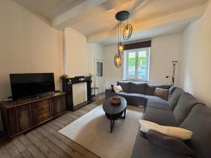 a living room with a couch and a tv at Chez Marraine in Nassogne