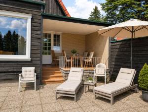 a patio with chairs and an umbrella and a table at HarzHaus Hahnenklee in Hahnenklee-Bockswiese