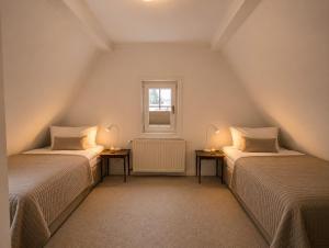 a attic room with two beds and a window at HarzHaus Hahnenklee in Hahnenklee-Bockswiese